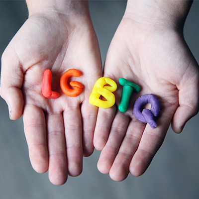 Hands holding the letters LGBTQ made from rainbow clay